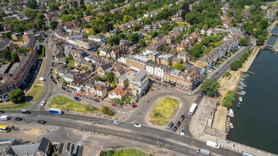 An aerial view of a residential neighbourhood in Enfield Town showing a busy roundabout with a central traffic island landscaped with greenery and small trees. Surrounding the roundabout are roads wit